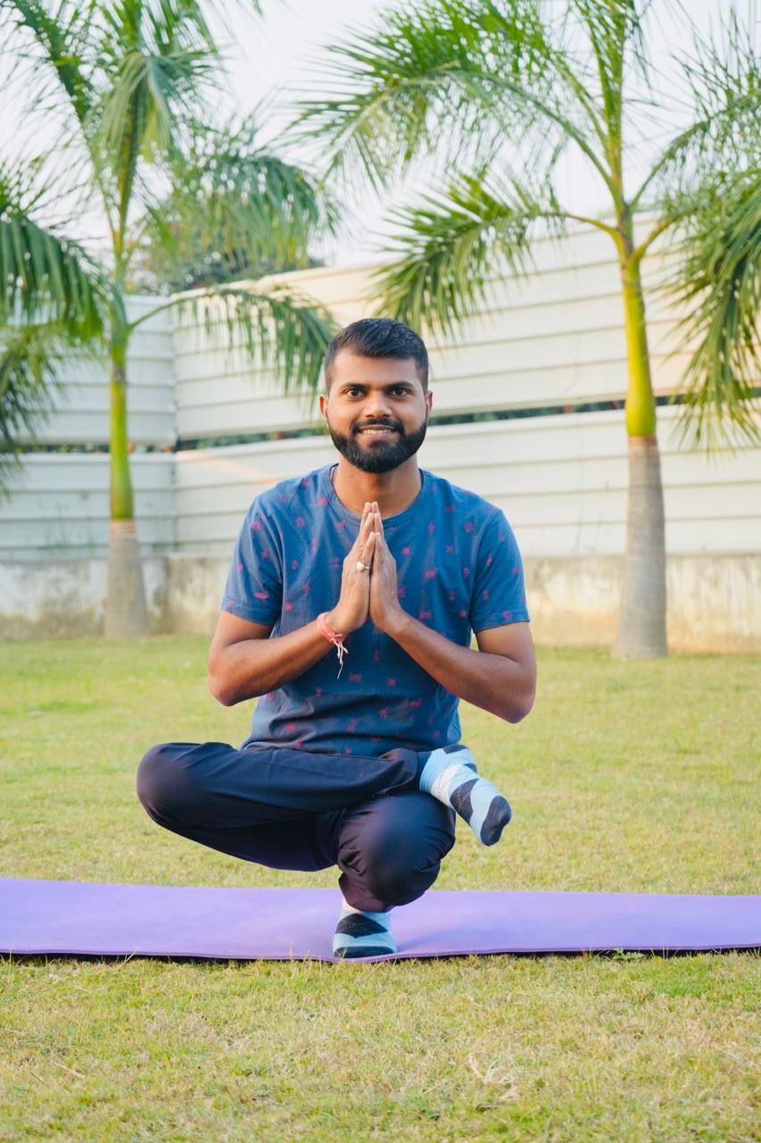 A VyayamVibes instructor practicing a balancing yoga pose outdoors